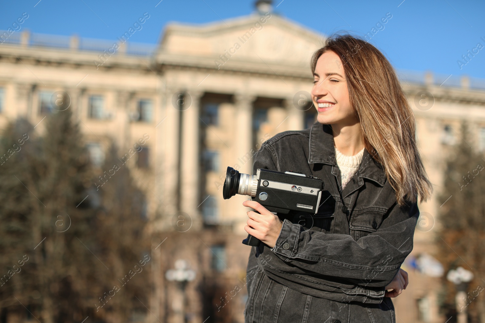 Photo of Beautiful young woman with vintage video camera on city street