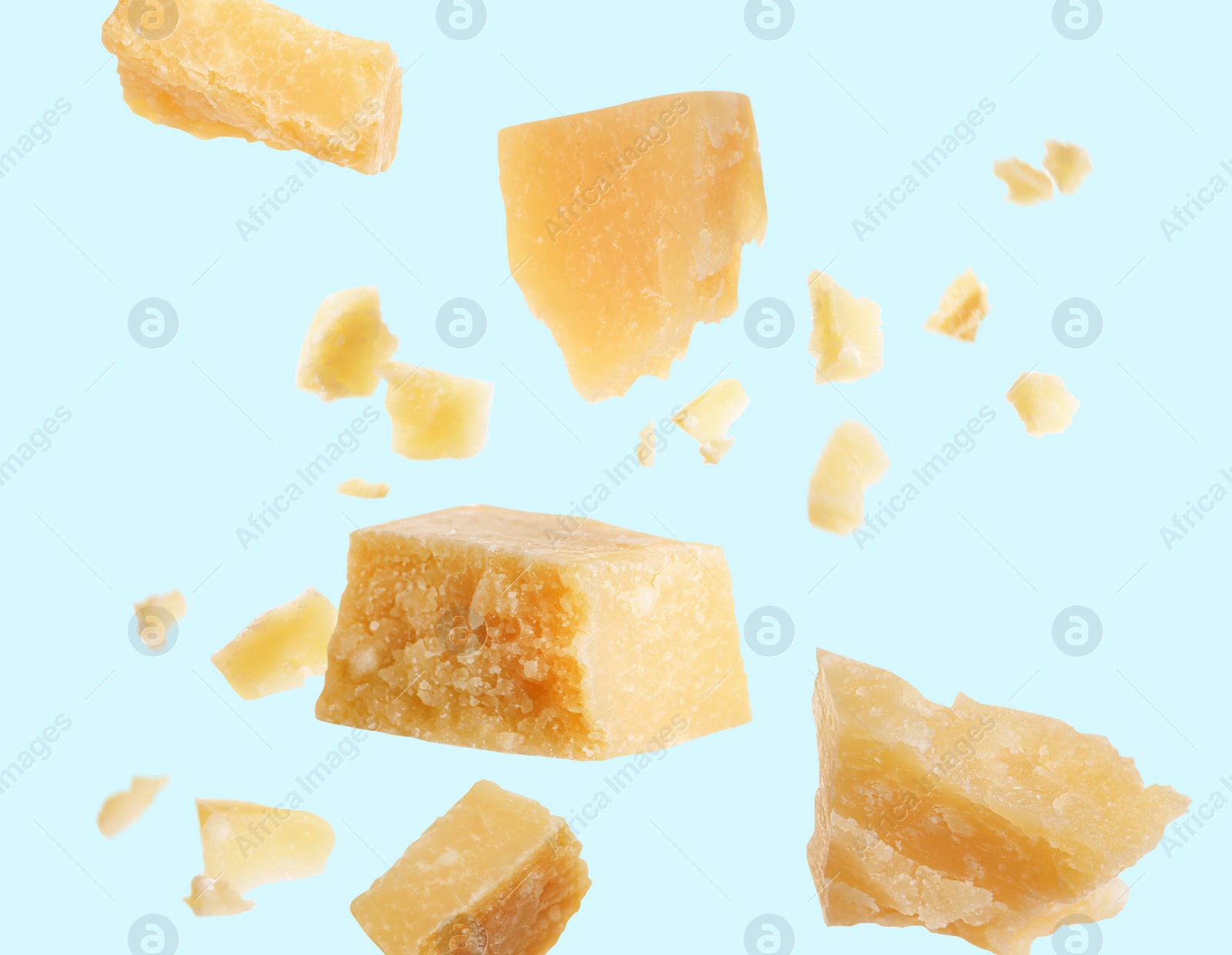 Image of Pieces of delicious parmesan cheese flying on light background