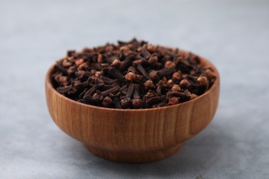 Aromatic cloves in bowl on gray table, closeup