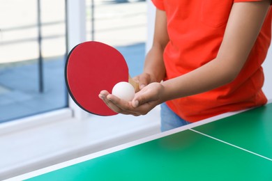 Photo of Little girl playing ping pong indoors, closeup