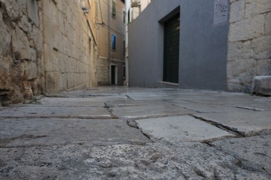 Empty paved alleyway between residential buildings in town