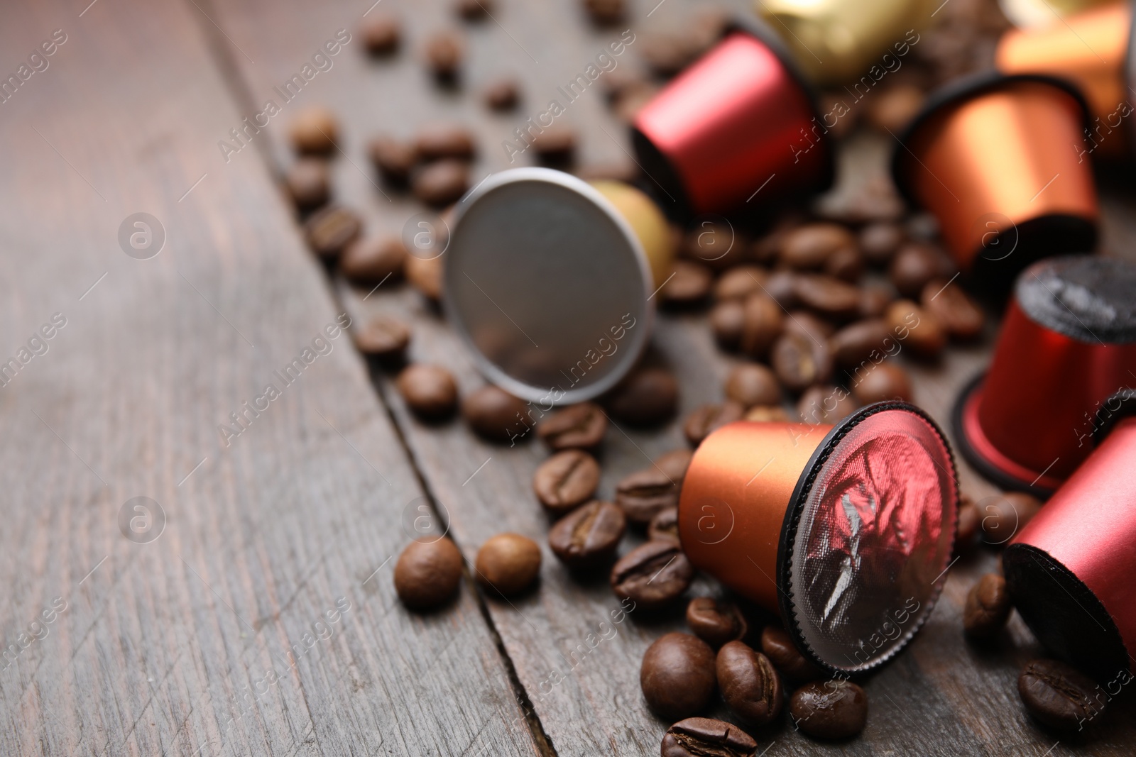 Photo of Many coffee capsules and beans on wooden table, closeup. Space for text