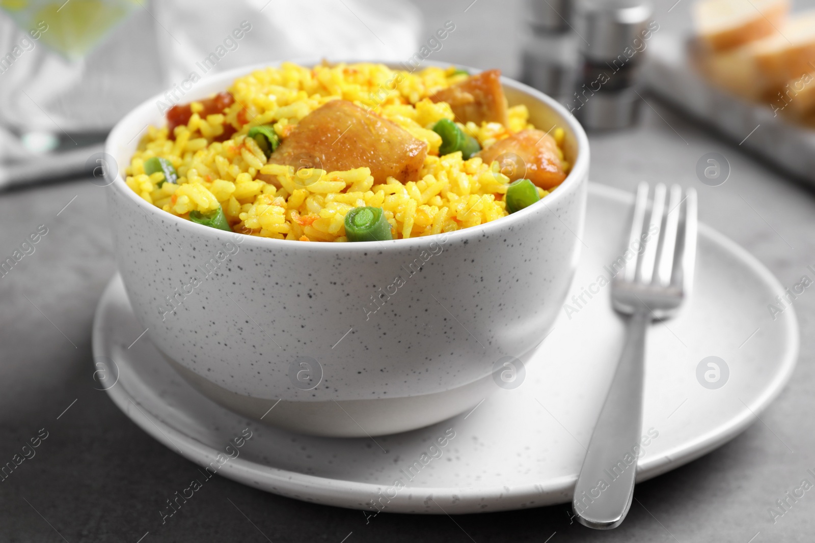 Photo of Delicious pilaf with chicken meat on light grey table, closeup
