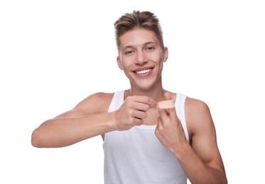 Photo of Handsome man putting sticking plaster onto finger on white background