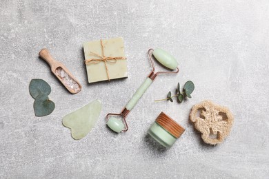 Photo of Flat lay composition with face roller and cosmetic products on light grey stone table