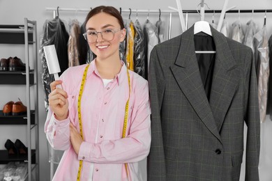 Young woman with lint roller at dry cleaner's