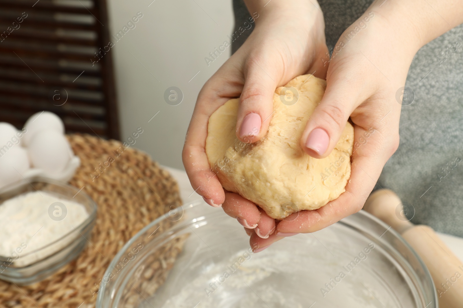 Photo of Woman holding raw dough at table, closeup