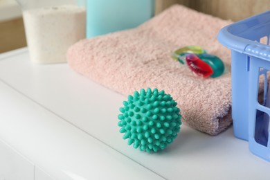 Turquoise dryer ball, detergents and towel on washing machine