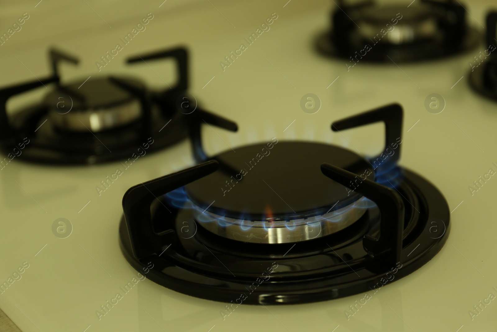 Photo of Gas burner of modern stove with burning blue flame, closeup