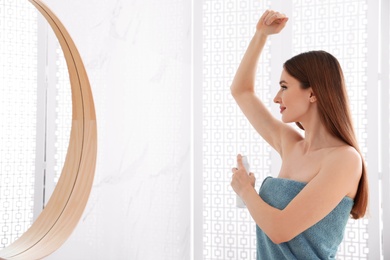 Photo of Beautiful young woman applying deodorant after shower in bathroom