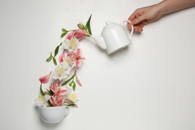 Pouring herbal tea. Woman with teapot, flowers and cup on light background, top view