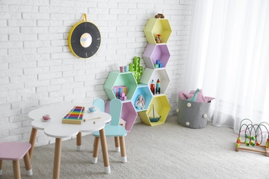 Child room interior with colorful shelves near brick wall