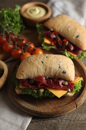 Photo of Delicious sandwiches with bresaola, cheese and lettuce served on wooden table