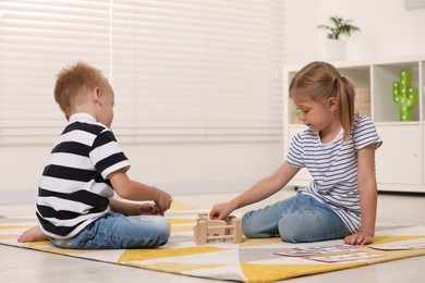 Photo of Little boy and girl playing with set of wooden animals indoors. Children's toys