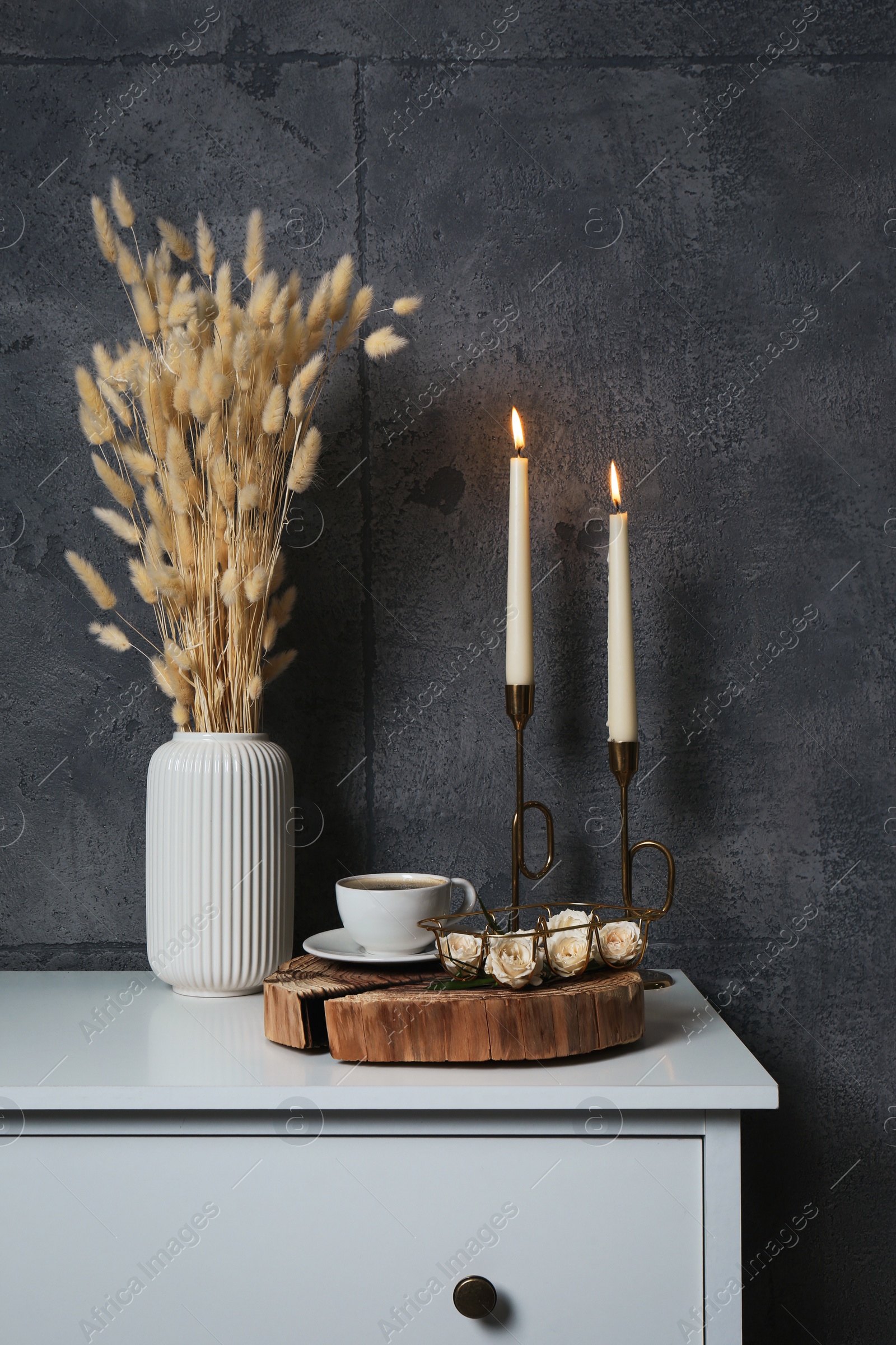 Photo of Cup of coffee, vase and other decor on white table near grey wall indoors. Interior design