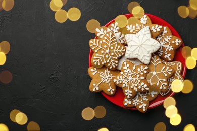 Tasty Christmas cookies with icing on black table, top view