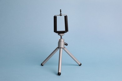 Photo of Modern stylish mobile tripod on light blue background