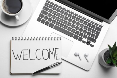 Notebook with word Welcome, coffee, gadgets and plant on white table, flat lay