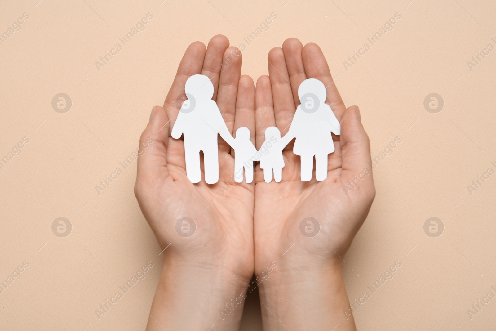 Photo of Woman holding paper family cutout on beige background, top view