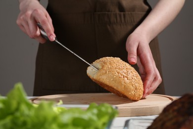 Photo of Woman making delicious vegetarian burger at table, closeup