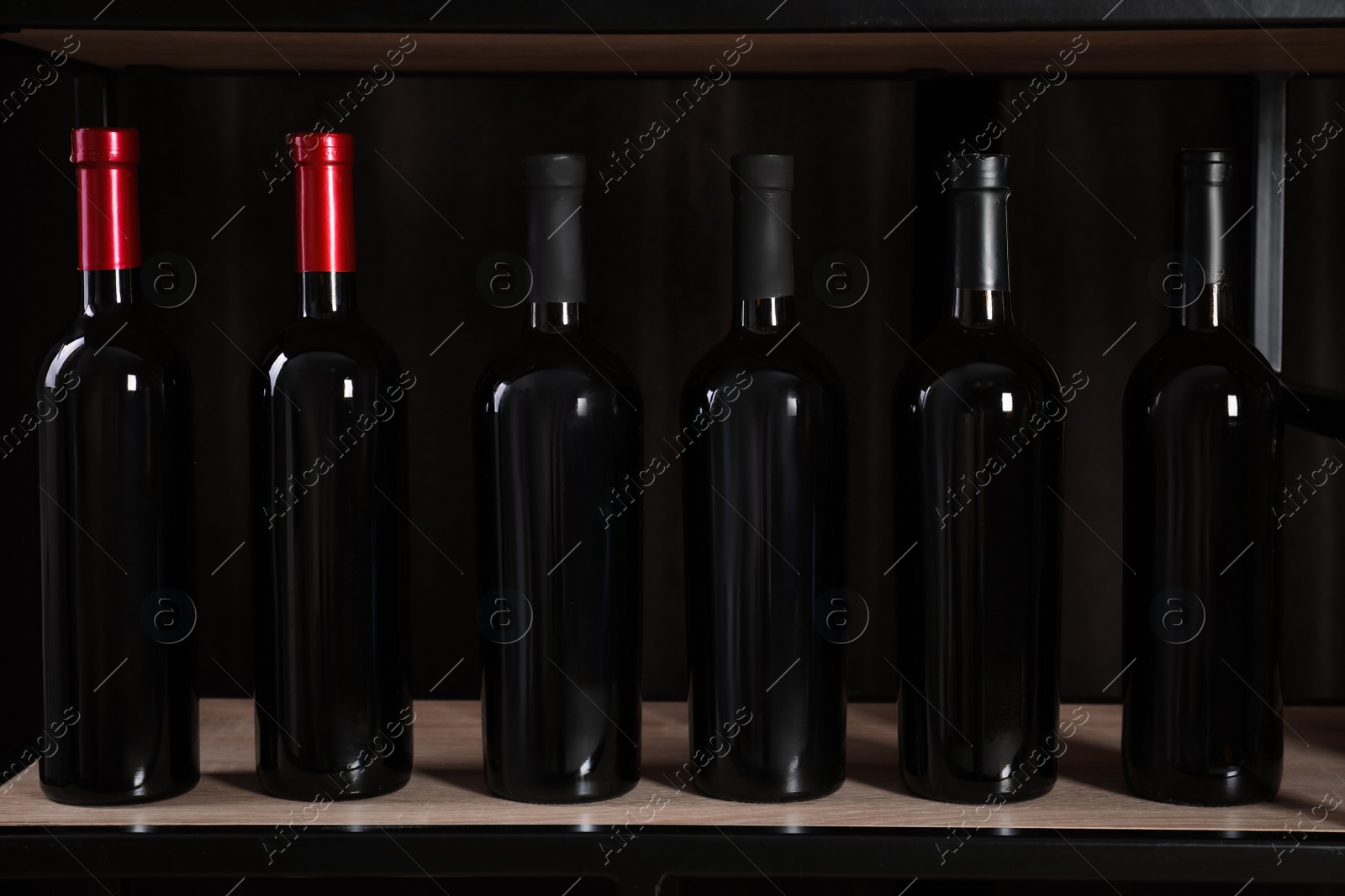 Photo of Bottles of wine on rack against black background