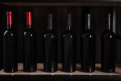 Photo of Bottles of wine on rack against black background