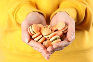 Photo of Woman holding handful of delicious gummy burger shaped candies, closeup