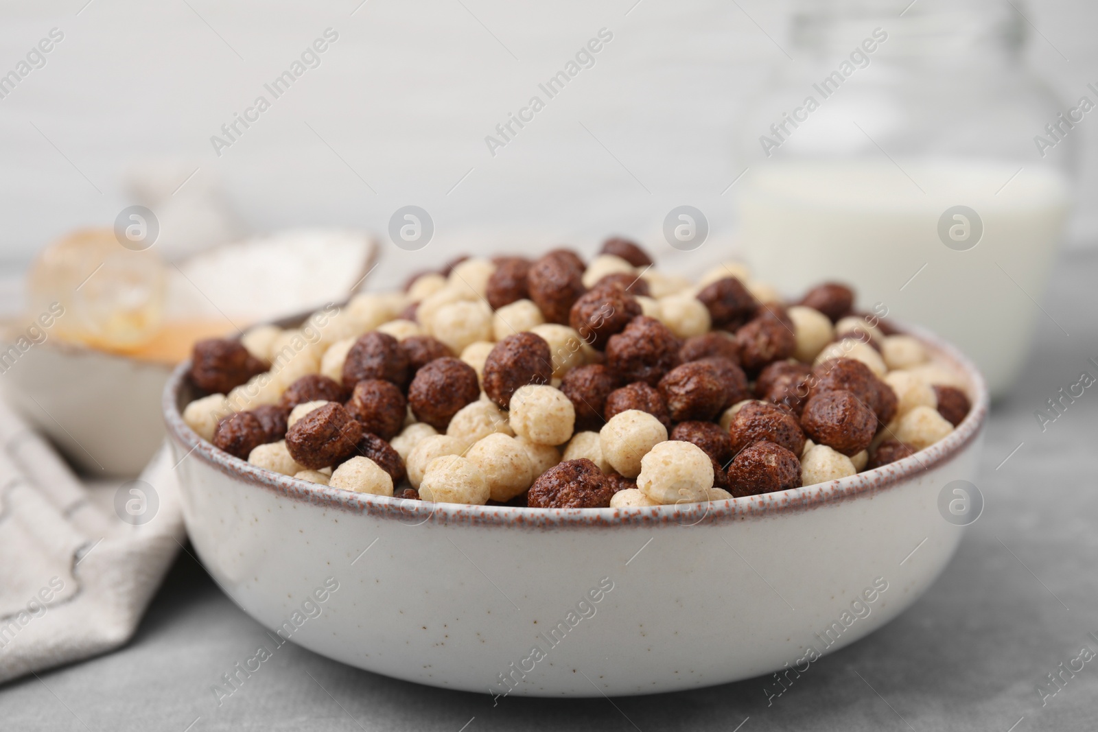 Photo of Tasty cereal balls in bowl on grey table, closeup