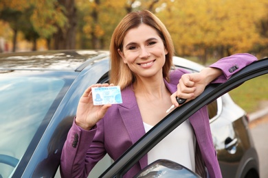 Woman holding driving license near open car