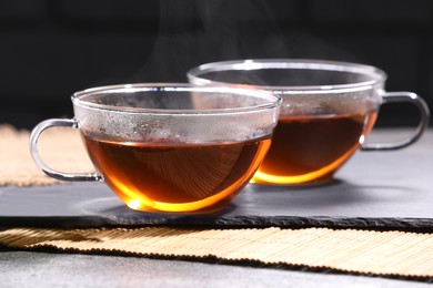 Aromatic hot tea in glass cups on grey table, closeup