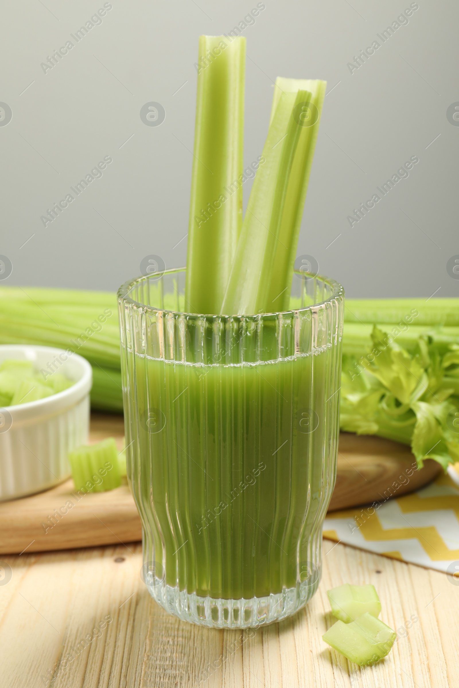 Photo of Glass of celery juice and fresh vegetables on wooden table