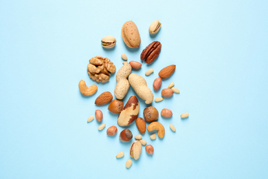 Flat lay composition with different nuts on light blue background