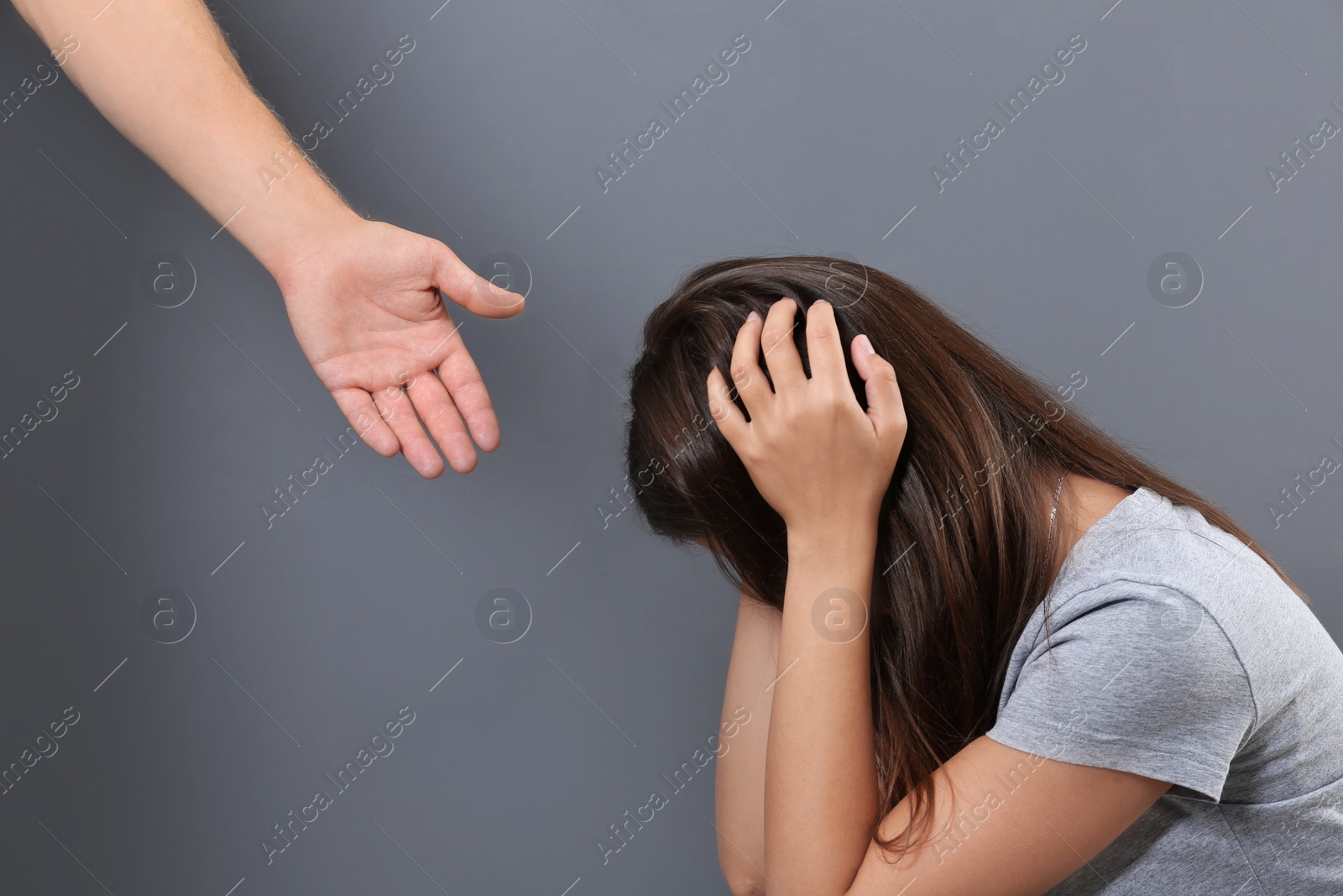 Photo of Man giving helping hand to depressed woman on gray background