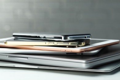Stack of electronic devices on white table, closeup
