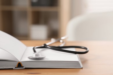 Book and stethoscope on wooden table indoors, space for text. Doctor education