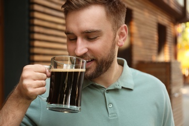 Photo of Handsome man with cold kvass outdoors. Traditional Russian summer drink