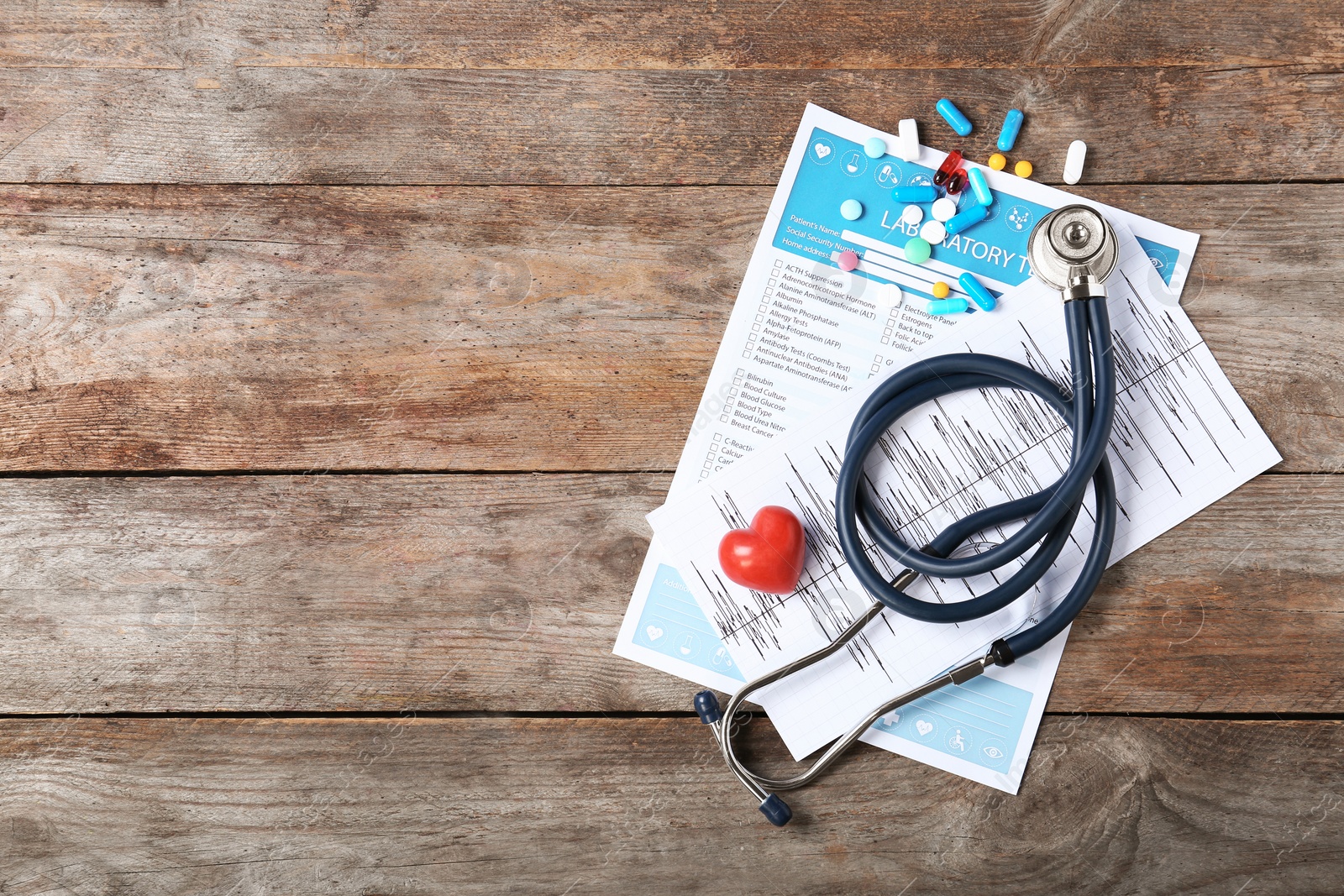 Photo of Flat lay composition with stethoscope and pills on wooden background. Cardiology service