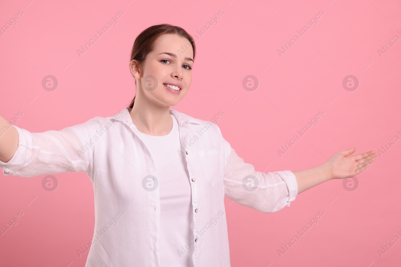 Photo of Happy woman inviting to come in against pink background