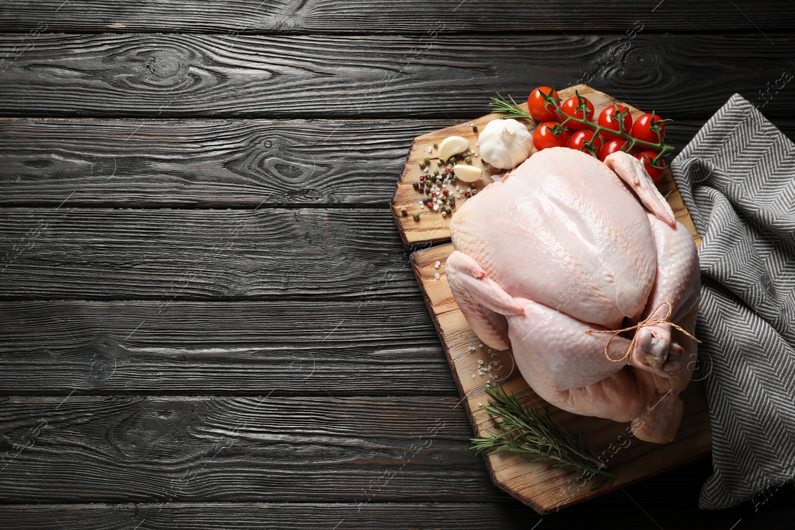 Photo of Board with raw turkey and ingredients on wooden background, top view. Space for text