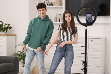 Smiling teenage bloggers dancing while streaming at home