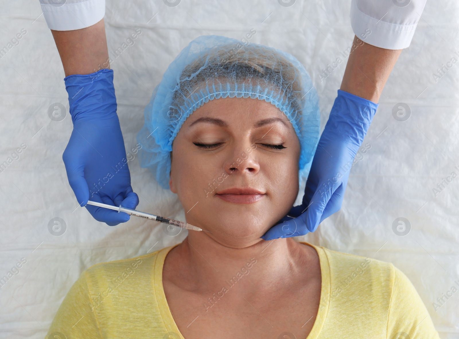 Photo of Mature woman with double chin receiving injection in clinic, above view