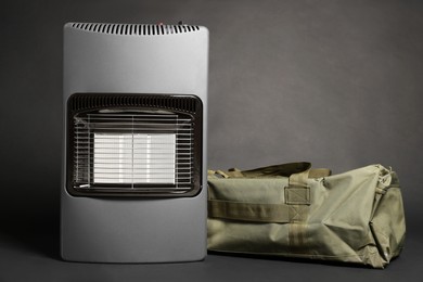 Photo of Modern gas heater and military bag on dark grey background