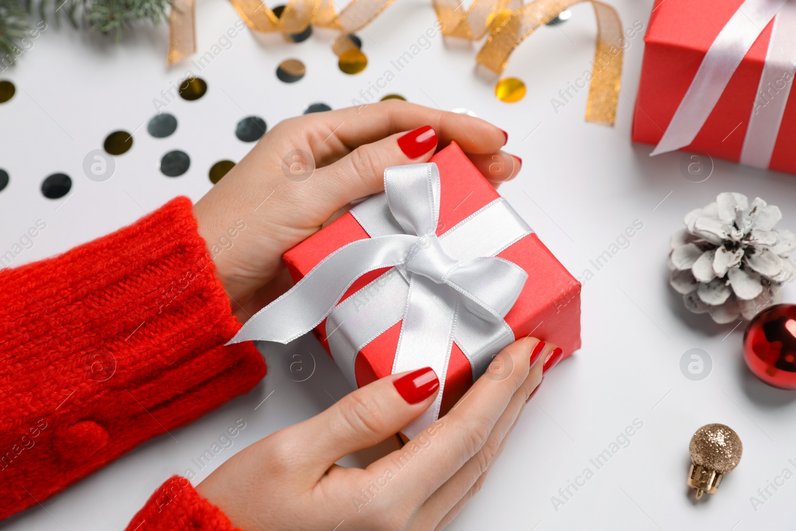 Photo of Woman holding gift box near Christmas decor on white background, closeup