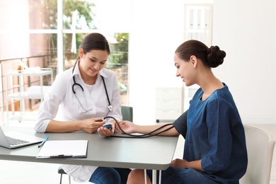 Doctor checking patient's blood pressure in hospital