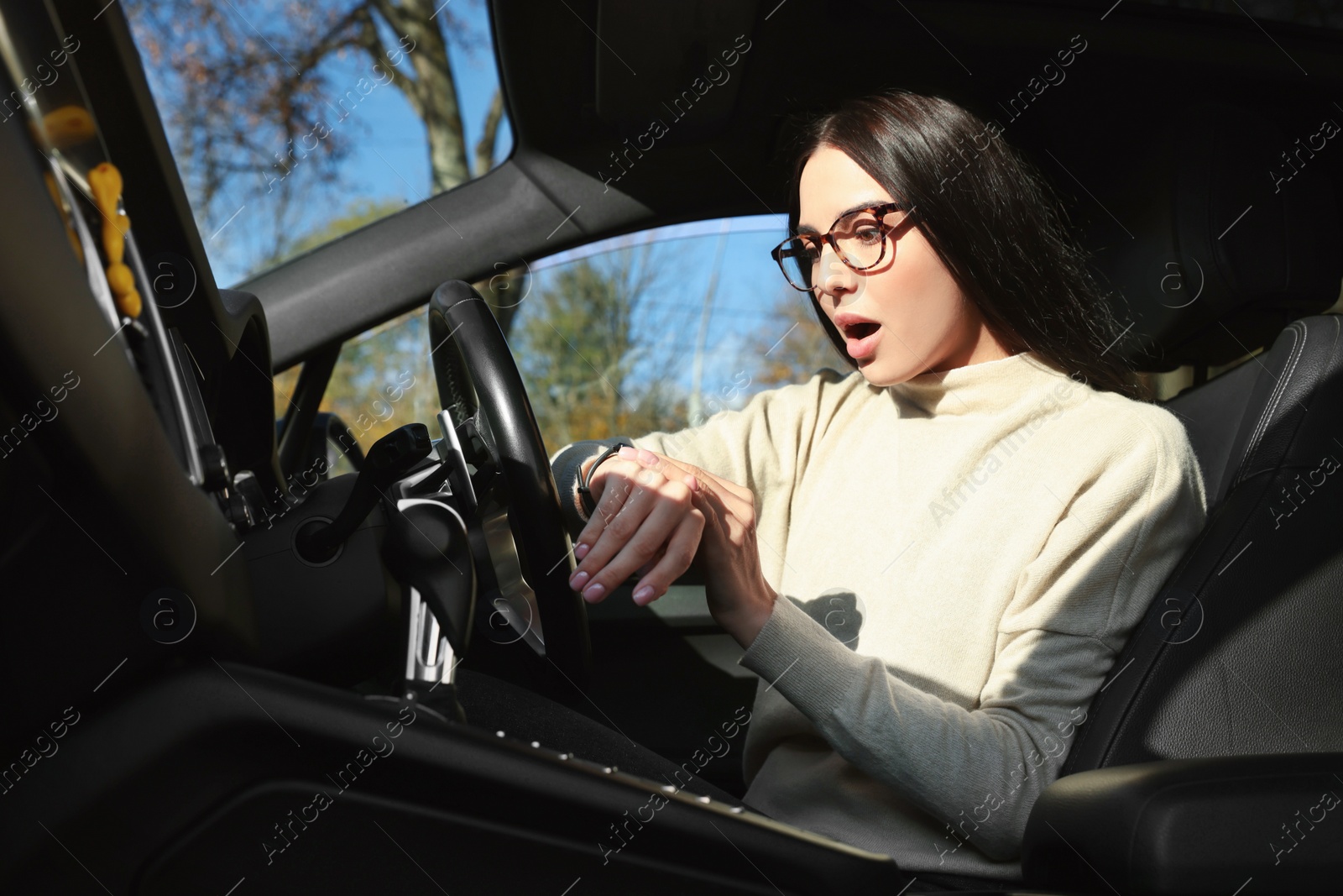 Photo of Emotional woman checking time on watch in car. Being late concept