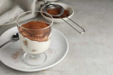 Photo of Delicious tiramisu in glass on light table. Space for text