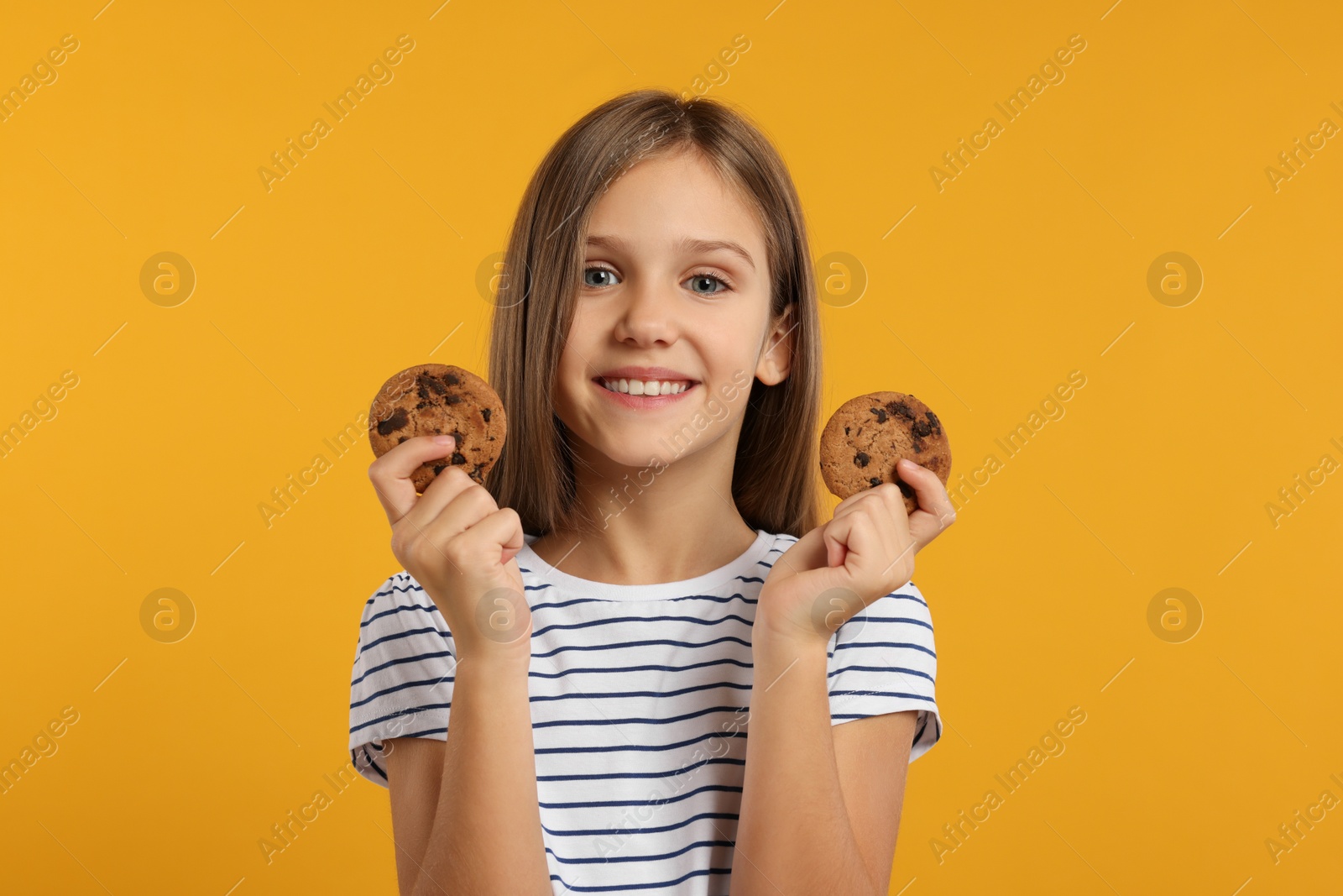 Photo of Cute girl with chocolate chip cookies on orange background