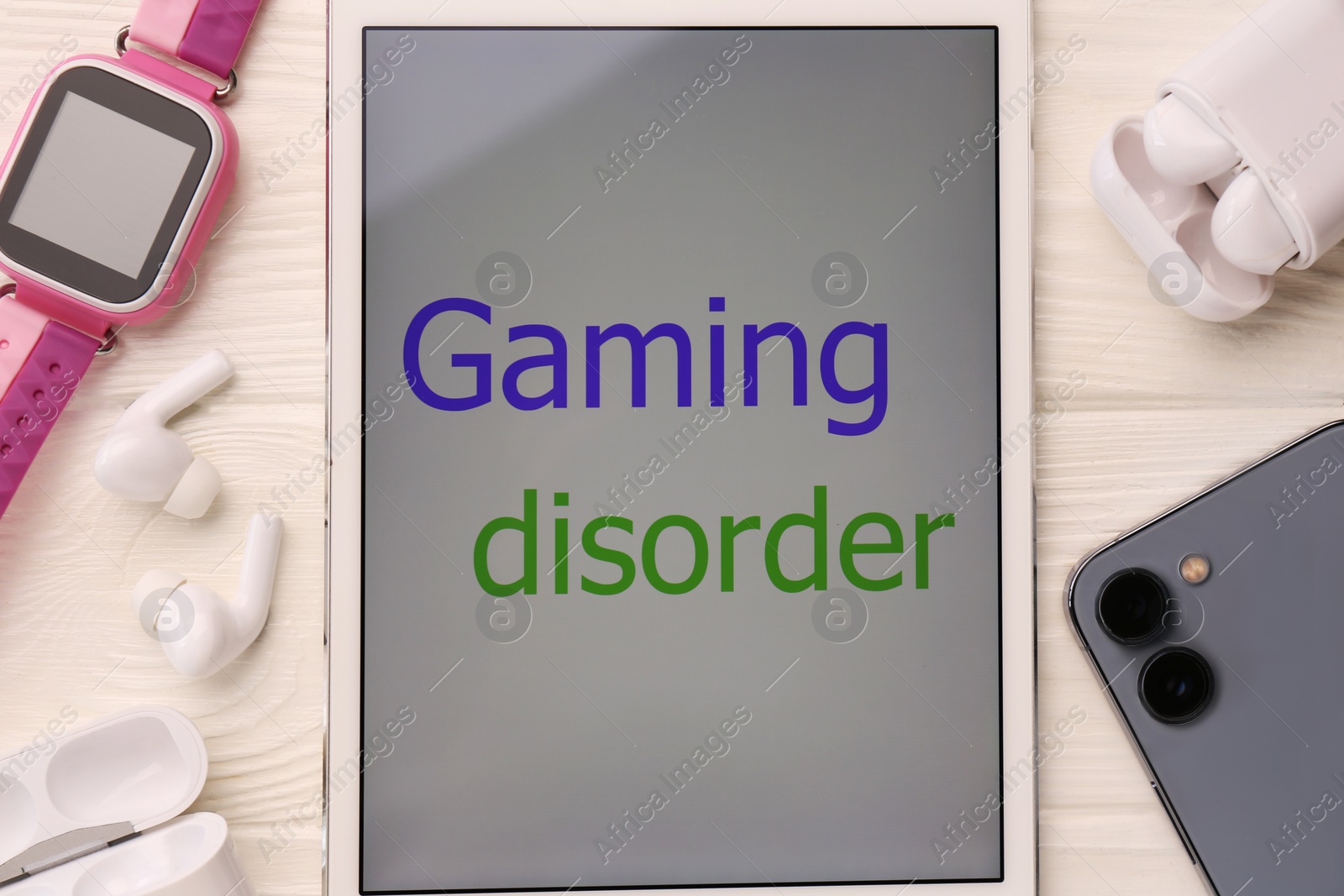 Photo of Tablet with phrase Gaming Disorder and devices on white wooden table, flat lay. Addictive behavior