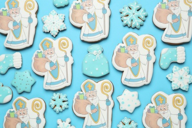 Photo of Tasty gingerbread cookies on light blue background, flat lay. St. Nicholas Day celebration