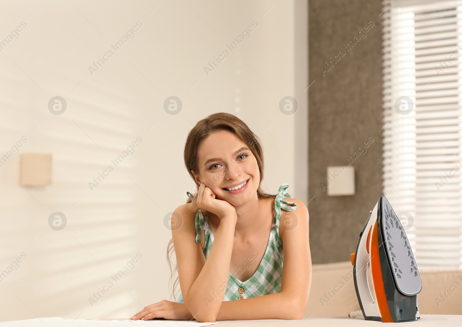 Photo of Pretty girl with iron near board at home